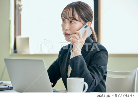 デスクで電話をする若い女性 97774247