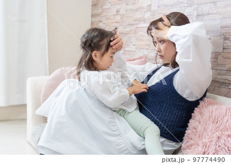 子どものおでこに手をあてて発熱を確かめる母親 子どものおでこに手をあてて発熱を確かめる母親 97774490