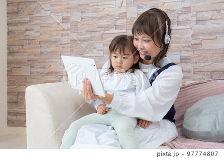 子供を抱きながらタブレットを操作する女性 子供を抱きながらタブレットを操作する女性 97774807