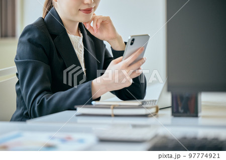 デスクでスマホを操作する若い女性 97774921