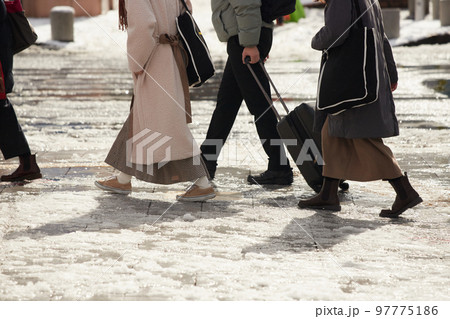 雪が溶けた地面で歩いている人々の姿 97775186