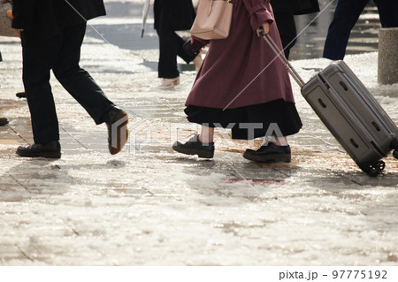 雪が溶けた地面で歩いている人々の姿 97775192