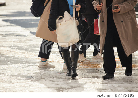 雪が溶けた地面で歩いている人々の姿 97775195