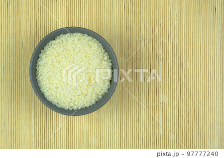 Rice in bowl on a straw background. Vegetarian organic product. Vintage view. Top view. Copy space. Rice in bowl on a straw background. Vegetarian organic product. Vintage view. Top view. Copy space. 97777240