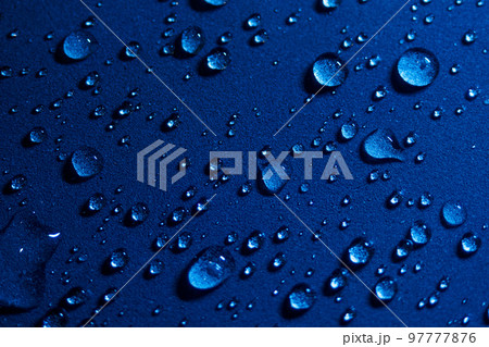 Round drops of water on dark blue background. Through transparent drops of water pass rays of light 97777876