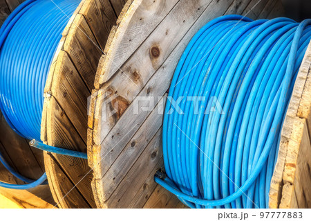 New blue power cable is wound on wooden coil. Background. Cable for laying underground.. New blue power cable is wound on wooden coil. Background. Cable for laying underground.. 97777883