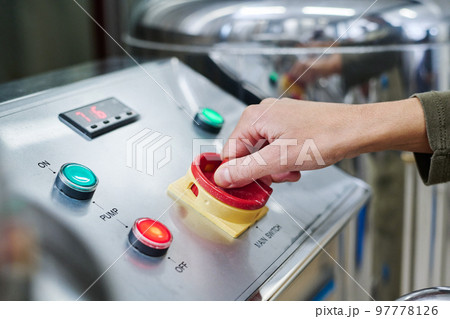 Close-up of engineer pushing the button on control panel to to start the work on equipment 97778126