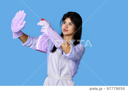 woman in gloves and cleaner apron with detergent sprayer 97779050