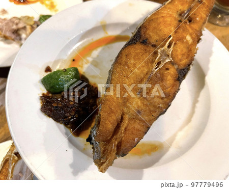 Delicious fried Spanish mackerel fish with spicy sauce and citrus served on white plate Delicious fried Spanish mackerel fish with spicy sauce and citrus served on white plate 97779496