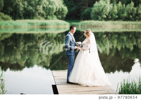 Beautiful bride and groom embracing and kissing on their wedding day outdoors 97780654