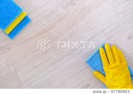 Top view. Cleaning concept in office, home. Hand in yellow rubber protective glove with micro fiber cloth wipes floor. Close up Top view. Cleaning concept in office, home. Hand in yellow rubber protective glove with micro fiber cloth wipes floor. Close up 97780663