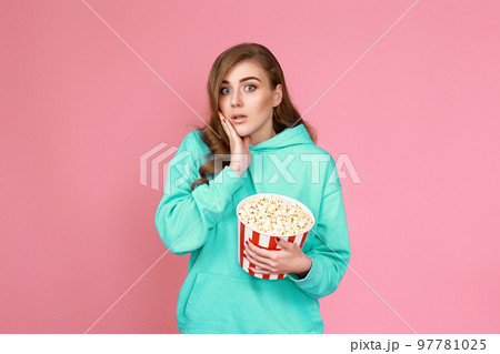 amazed brunette woman holding bucket of popcorn 97781025
