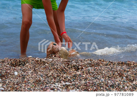 Active children summer vacation at sea. Boy in green shorts is relaxing on sea coast. Sunny summer day. 97781089