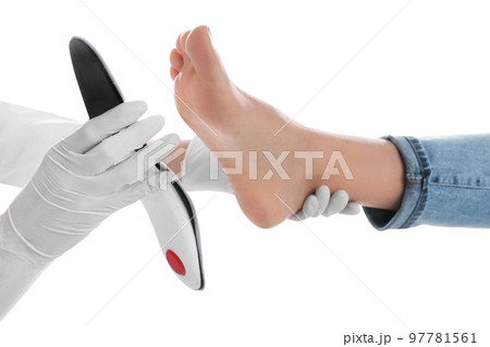 Orthopedist fitting insole on patient's foot against white background, closeup 97781561