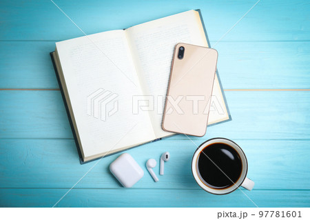 Book, coffee, earphones and mobile phone on light blue wooden table, flat lay Book, coffee, earphones and mobile phone on light blue wooden table, flat lay 97781601