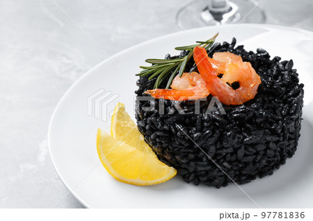 Delicious black risotto with shrimps and lemon on marble table, closeup Delicious black risotto with shrimps and lemon on marble table, closeup 97781836