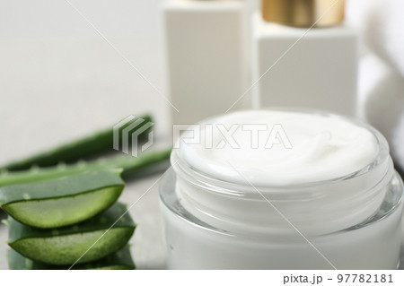 Open jar of cream and cut aloe on table, closeup. Organic cosmetics 97782181