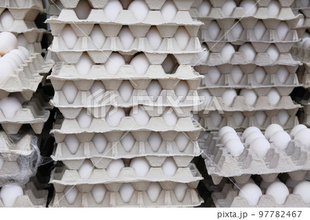 Chicken white eggs in cardboard boxes stacked in rows in store. Eggs in package. 97782467
