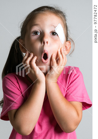Funny, cute, adorable dark haired little girl with injury and patch on face, wear pink shirt. Afraid parents reaction Funny, cute, adorable dark haired little girl with injury and patch on face, wear pink shirt. Afraid parents reaction 97782472