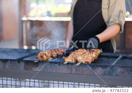 Man roasts a barbecue on an open fire.Street food and outdoor cooking concept 97782522