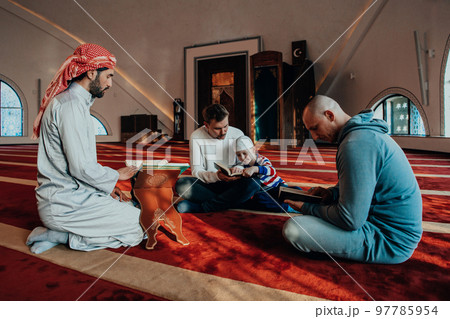 A group of Muslims reading the holy book of the Quran in a modern mosque during the Muslim holiday of Ramadan A group of Muslims reading the holy book of the Quran in a modern mosque during the Muslim holiday of Ramadan 97785954