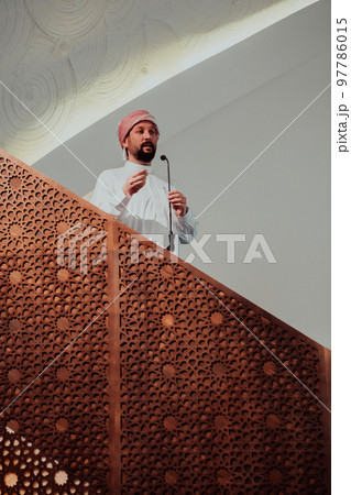 Muslims arabic Imam has a speech on friday afternoon prayer in mosque. Muslims have gathered for the friday afternoon prayer in mosque and are listening to the speech of imam Muslims arabic Imam has a speech on friday afternoon prayer in mosque. Muslims have gathered for the friday afternoon prayer in mosque and are listening to the speech of imam 97786015