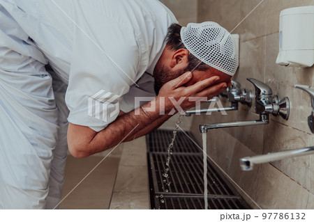 A Muslim performing ablution. Ritual religious cleansing of Muslims before performing prayer. The process of cleansing the body before prayer 97786132