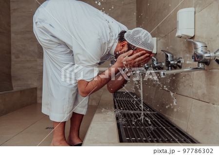 A Muslim performing ablution. Ritual religious cleansing of Muslims before performing prayer. The process of cleansing the body before prayer 97786302