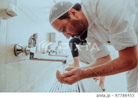 A Muslim performing ablution. Ritual religious cleansing of Muslims before performing prayer. The process of cleansing the body before prayer A Muslim performing ablution. Ritual religious cleansing of Muslims before performing prayer. The process of cleansing the body before prayer 97786455