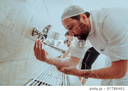 A Muslim performing ablution. Ritual religious cleansing of Muslims before performing prayer. The process of cleansing the body before prayer A Muslim performing ablution. Ritual religious cleansing of Muslims before performing prayer. The process of cleansing the body before prayer 97786461