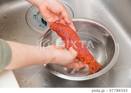【イクラの醤油漬けを作るために、塩を入れたぬるま湯に生イクラを入れる】 97786593