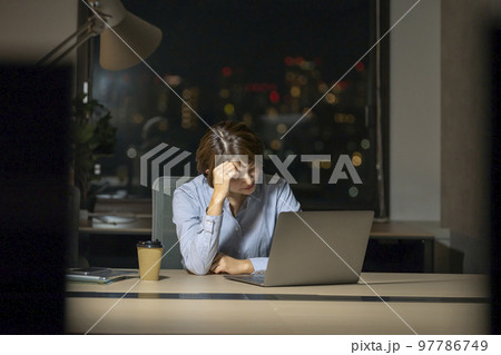夜のオフィスで頭を抱えるビジネスウーマン 97786749