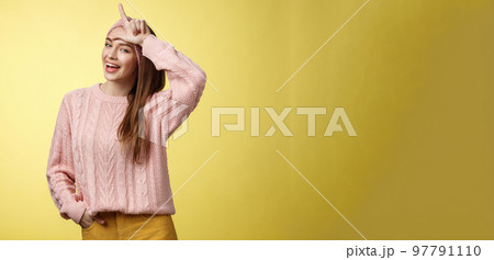 Attractive triumphing arrogant and confident cute glamourous woman in knitted sweater, headband showing l letter on forehead, loser sign and laughing over lost team, mocking having fun 97791110
