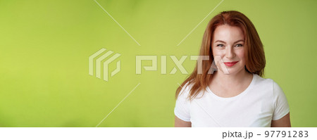 Enthusiastic smiling redhead middle-aged woman grinning joyfully alluring motivated gaze camera determined reach goal happy watching grandson playing yard pleased have perfect family green background 97791283