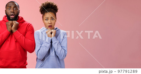 Upset worried two siblings watching together scary disturbing horror movie gasping frowning cringing shock intense emotions press hands chest widen eyes terrified standing nervous pink background 97791289