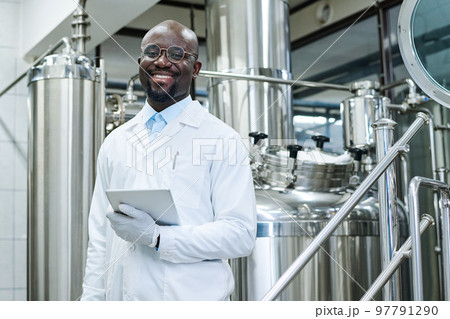 Portrait of African American engineer in white coat smiling at camera working at production factory 97791290