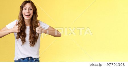 Cheerful suportive energized cute european cute curly-haired girl show thumbs-up approval rooting for friend excellent effort nodding accepting great awesome work done stand yellow background Cheerful suportive energized cute european cute curly-haired girl show thumbs-up approval rooting for friend excellent effort nodding accepting great awesome work done stand yellow background 97791308