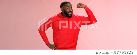 Charming cheeky friendly african-american strong guy smiling broadly proudly showing biceps raise one hand bragging muscles attend gym recommend you get fit, standing pink background 97791825