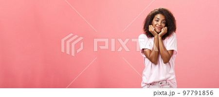 Dreamy nostalgic african american girlfriend with curly hairstyle sighing leaning head on palms and smiling gently as if imaging or gazing at boyfriend with affection having feelings for friend 97791856