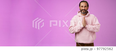 Peaceful attractive bearded mature mail model in trendy pink hoodie press palms together namaste praying gesture smiling delighted relaxed bowing buddhism faith, appreciating help, look thankful Peaceful attractive bearded mature mail model in trendy pink hoodie press palms together namaste praying gesture smiling delighted relaxed bowing buddhism faith, appreciating help, look thankful 97792562