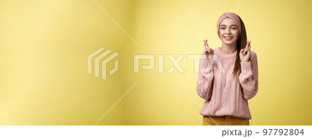 Cross my fingers for you. Supportive cute young european girlfriend wearing sweater, glamour headband making luck, wish gesture smiling hopeful having faith dream come true over yellow background Cross my fingers for you. Supportive cute young european girlfriend wearing sweater, glamour headband making luck, wish gesture smiling hopeful having faith dream come true over yellow background 97792804