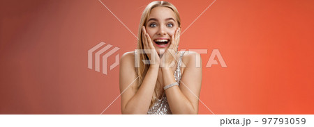 Amazed speechless excited attractive young woman blond long hair press palms cheeks blushing amused cannot believe see popular super star glancing thrilled amazement, surprised red background 97793059