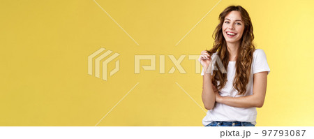 Lively joyful happy cute brunette curly long hairstyle playing curl laughing joyfully having funny amusing conversation smiling toothy white perfect smile stand yellow background relaxed 97793087