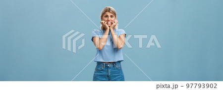 Attractive adult girl scared dad knows her secret standing over blue background frowning biting fingernails worrying and feeling anxious thinking about bad consequences insecure and nervous 97793902