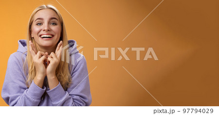 Lucky optimistic cute positive smiling blond girl grinning excited cross fingers making wish dreaming desire come true anticipating good news praying orange background waiting results Lucky optimistic cute positive smiling blond girl grinning excited cross fingers making wish dreaming desire come true anticipating good news praying orange background waiting results 97794029
