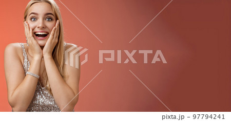 Amazed speechless excited attractive young woman blond long hair press palms cheeks blushing amused cannot believe see popular super star glancing thrilled amazement, surprised red background 97794241