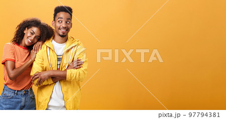 Guy feeling happy girl lean on his shoulder grinning and chuckling from happiness standing pleased and joyful over orange background while woman hugging best friend upbeat she can rely on him 97794381