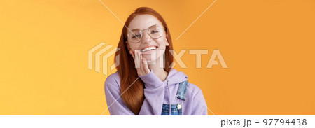 Charismatic happy tender redhead smiling european girl 20s glasses hoodie denim overalls having fun enjoying summer holidays chilly evening laughing joyfully touch pure clear skin, orange background Charismatic happy tender redhead smiling european girl 20s glasses hoodie denim overalls having fun enjoying summer holidays chilly evening laughing joyfully touch pure clear skin, orange background 97794438