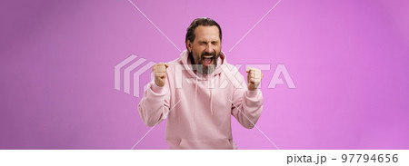 Accomplished happy joyful triumphing mature 40s bearded man grey hair yelling yes thrilled joyfully clench fists celebrating success win lottery become millionaire, standing purple background 97794656
