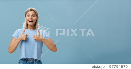 You did great proud of you. Portrait of satisfied and fascinated attractive happy girlfriend in casual t-shirt showing thumbs up and smiling broadly being supportive and cheerful over blue wall You did great proud of you. Portrait of satisfied and fascinated attractive happy girlfriend in casual t-shirt showing thumbs up and smiling broadly being supportive and cheerful over blue wall 97794670